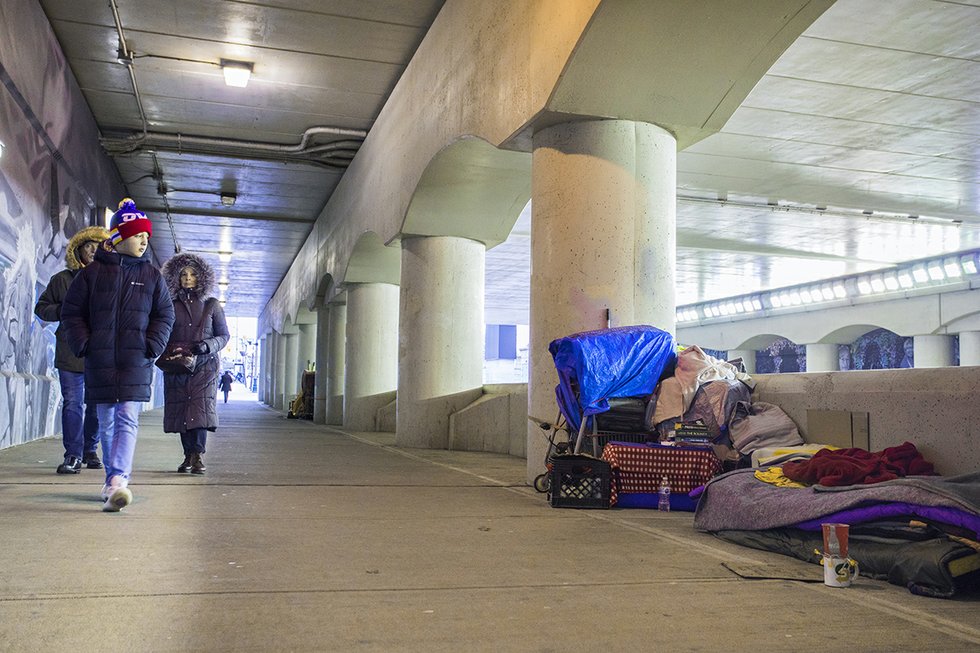 A photo of people walking past a homeless encampment near Union Station in Toronto in winter 2020.
