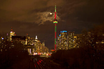 A photo of the CN Tower at night lit up with Christmas lights