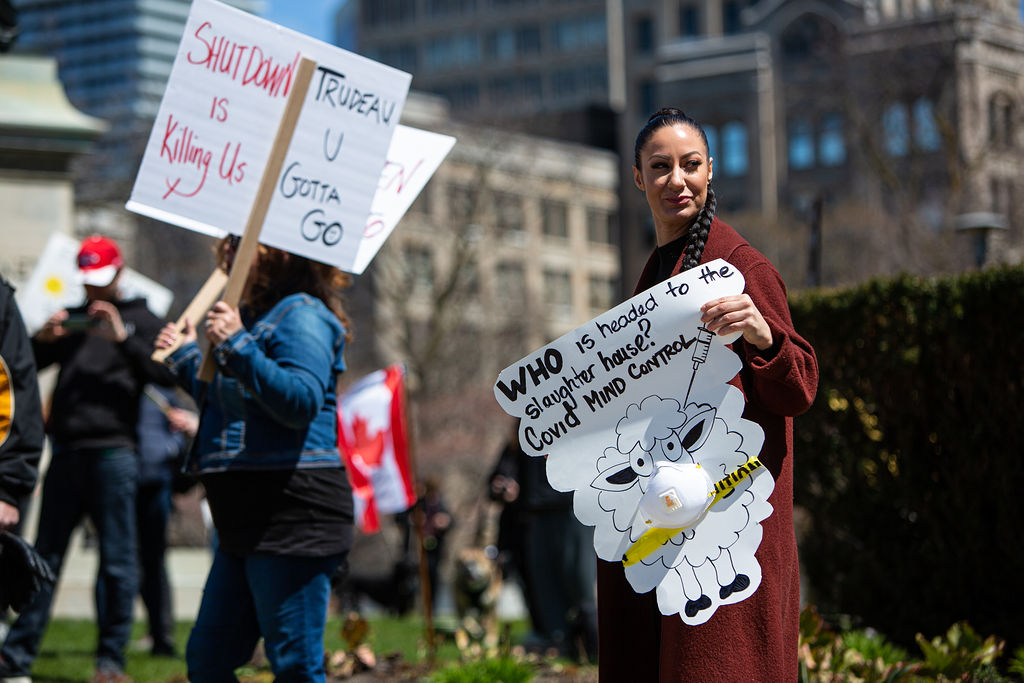 Protesters holds a signs at an anti-lockdown protest at Queens Park, April 25th, 2020.