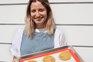 A photo of Lucy Kirby from Breadhead holding a tray of cookies