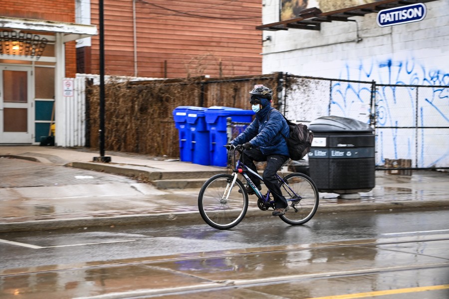A photo of a person riding a bike in the rain while wearing a mask