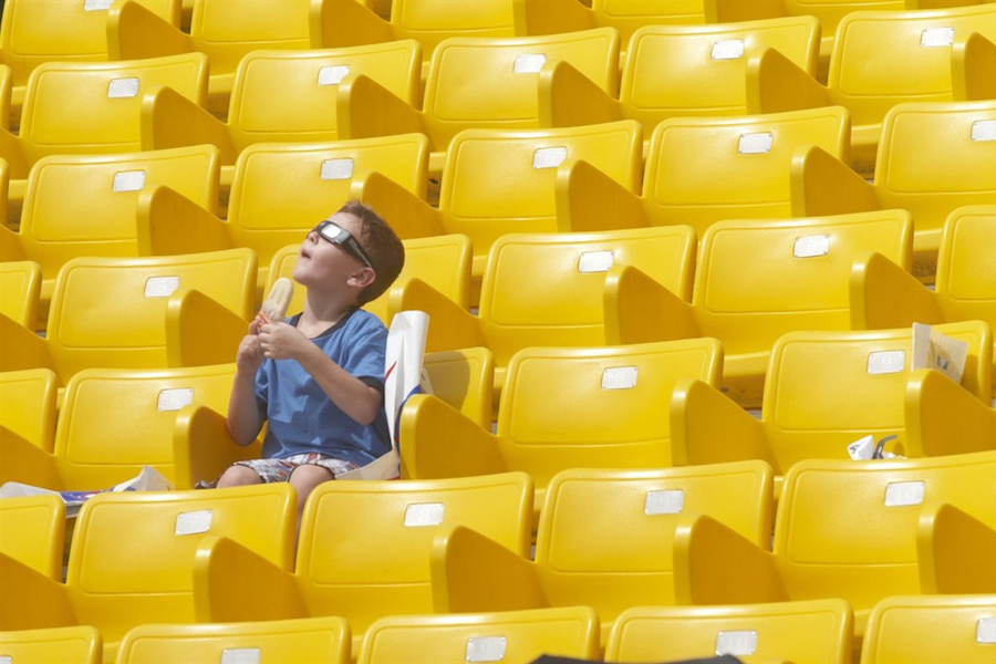 A boy looks at the sky seated alone in yellow seats in All Light, Everywhere, one of the must-see films at Hot Docs 2021