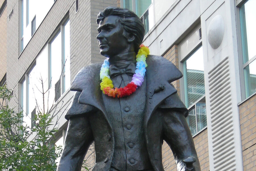 A photo of the Alexander Wood statue with a rainbow garland