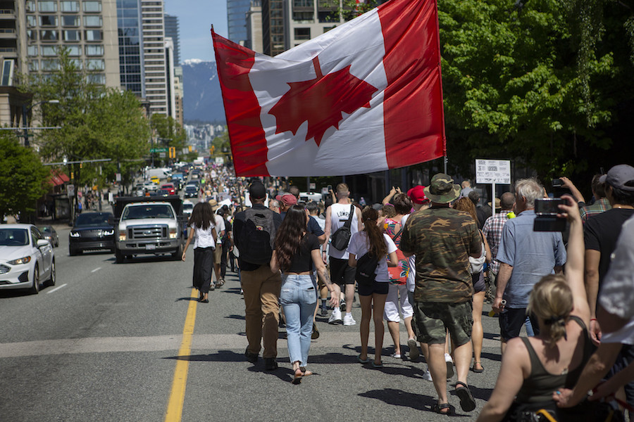 Protestors carry the Canadian flag upside down in Vancouver on May 15, 2021