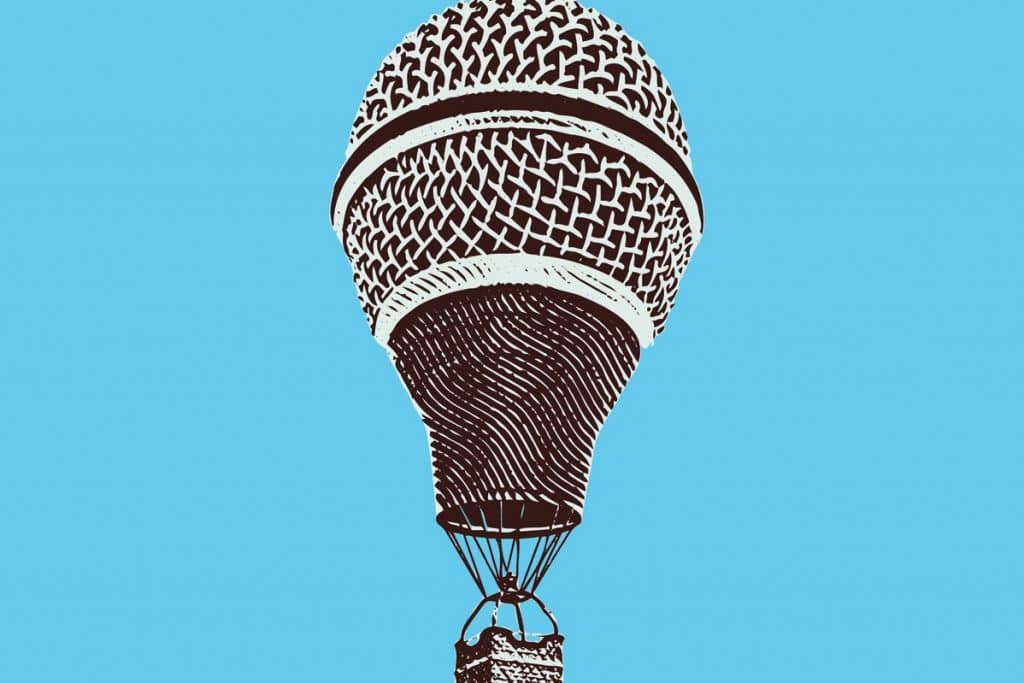Unique hot air balloon with a microphone design, representing creative arts and entertainment, against a bright blue sky.