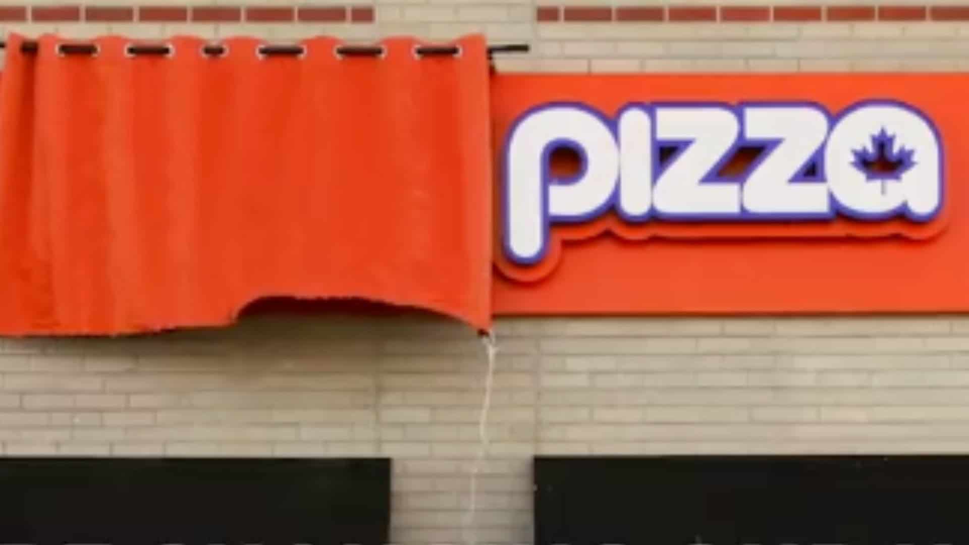 Bright orange pizza restaurant sign with a blue and white logo, featuring Canada’s maple leaf, outside a building in Toronto, Ontario, showcasing local pizzerias, Toronto food scene, and pizza delivery.