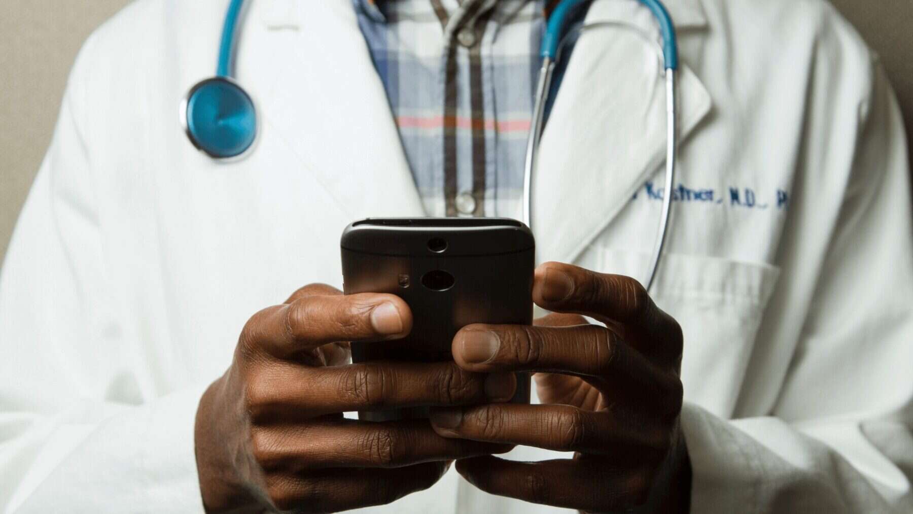Healthcare professional using a smartphone with stethoscope, modern medical technology, healthcare communication, doctor telemedicine, medical staff working, digital health technologies.