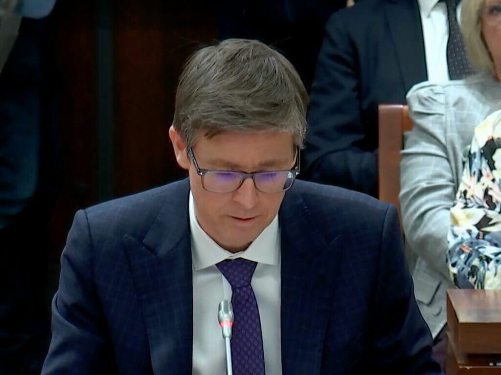 Professional man in suit speaking at a city council meeting in Toronto.