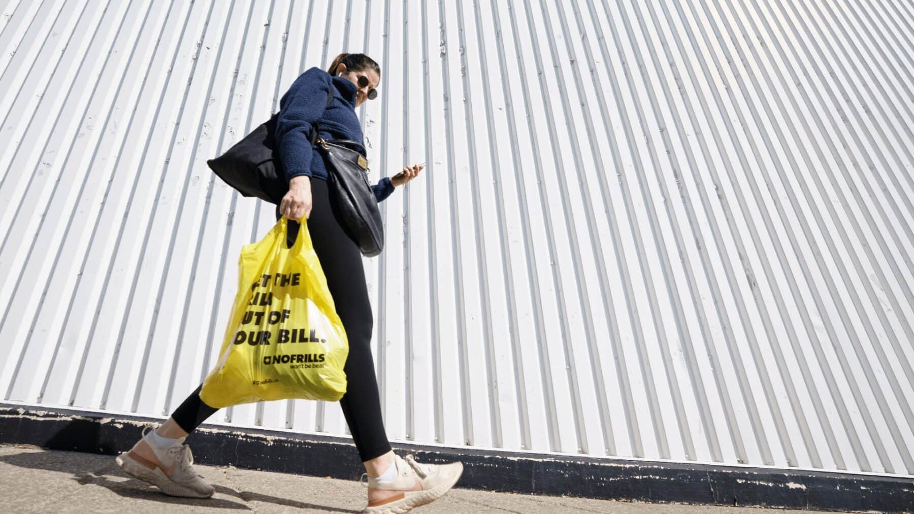 Young woman walking with shopping bags next to Toronto modern building, city lifestyle, shopping, street fashion, urban environment, NOW Toronto, Toronto lifestyle.