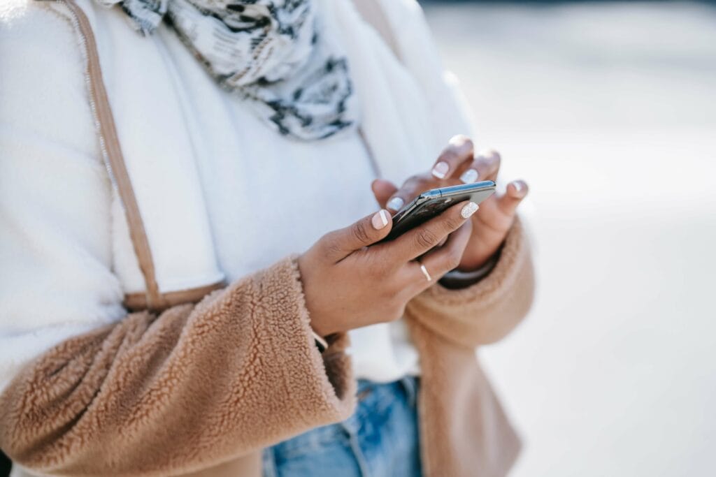 Close-up of a person holding and using a smartphone outdoors, showcasing mobile technology and communication.