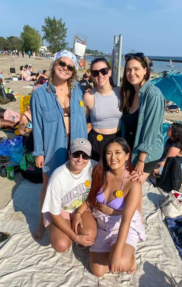 Colorful group of friends relaxing at Toronto beach with umbrellas, beach accessories, and sunny weather, capturing the vibrant outdoor summer scene in Toronto.