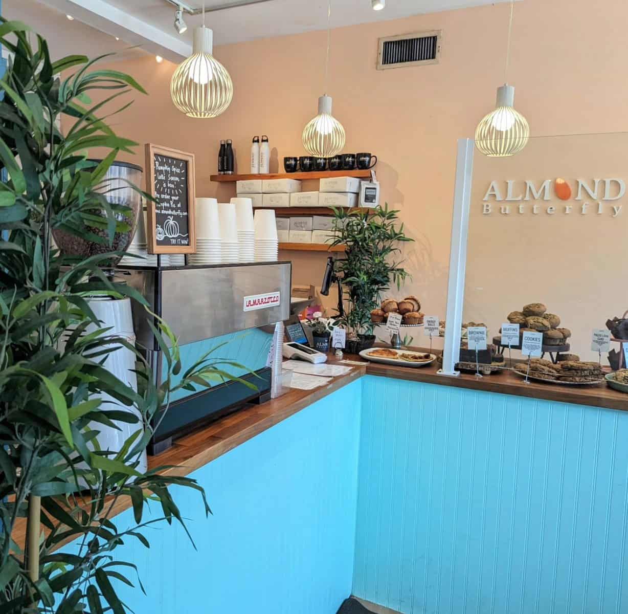 Bright bakery interior with display of diverse baked goods, modern pendant lighting, and cozy decor at Almond Butterfly bakery, Toronto.
