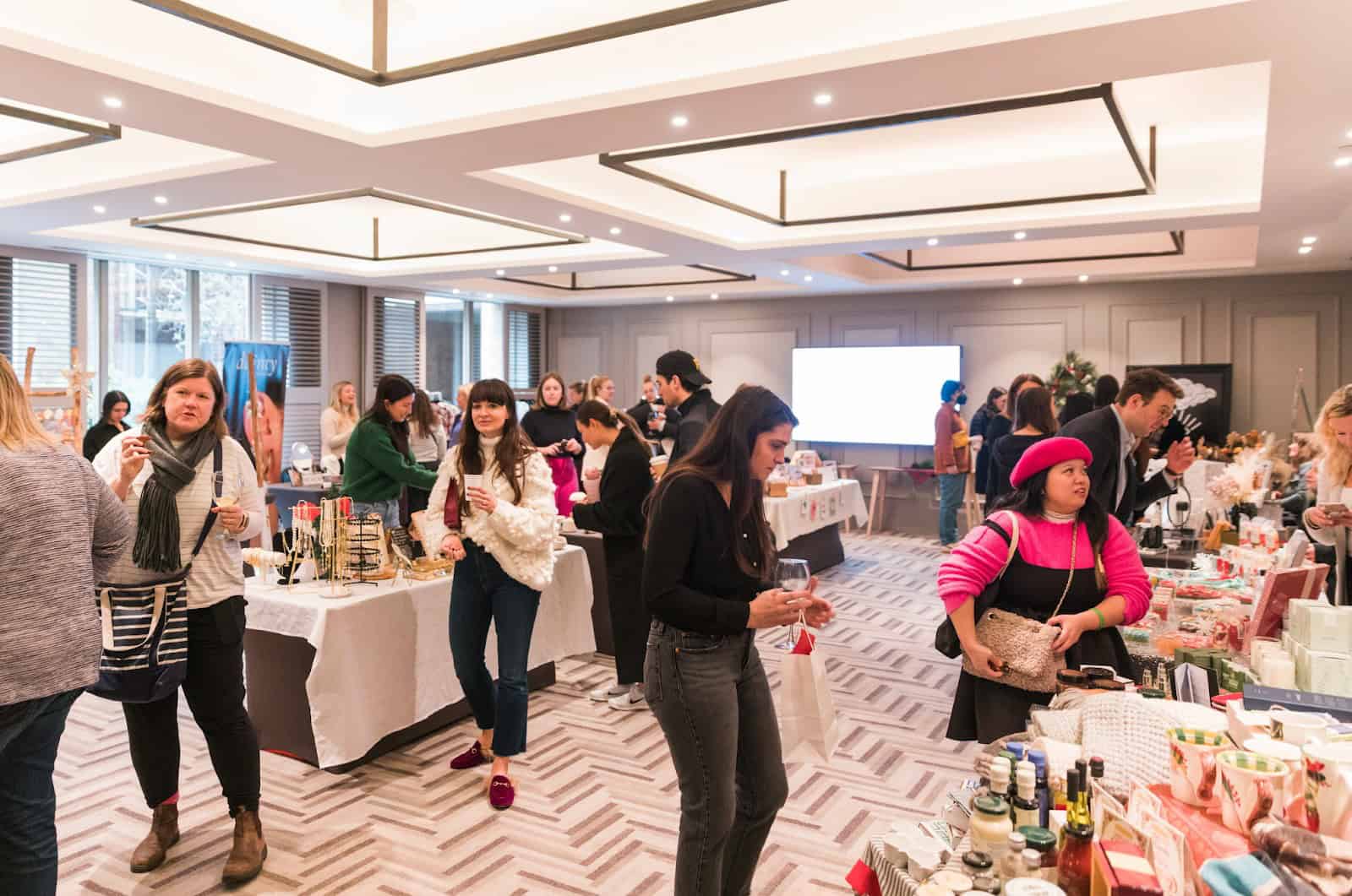 Vibrant indoor shopping event in Toronto with diverse vendors selling handmade crafts, cosmetics, and festive gift items, attracting local residents and shoppers.