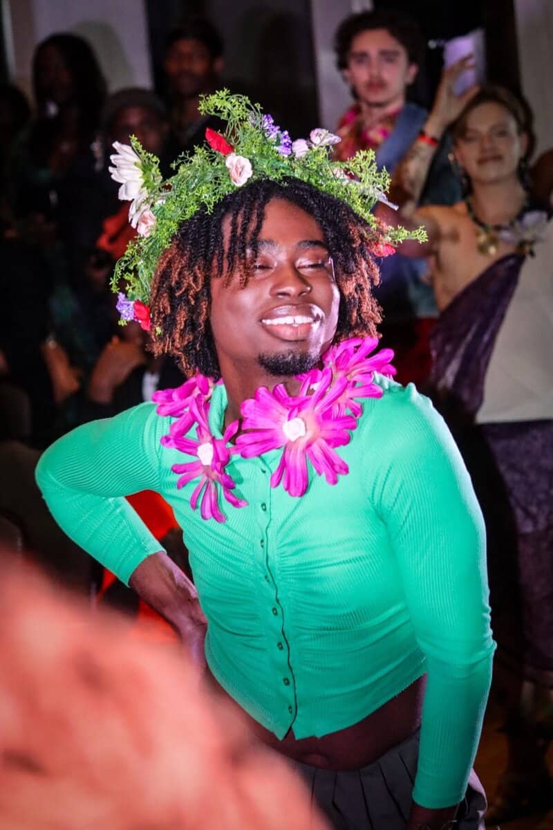 Vibrant person wearing floral crown and bright green shirt at Toronto cultural event.