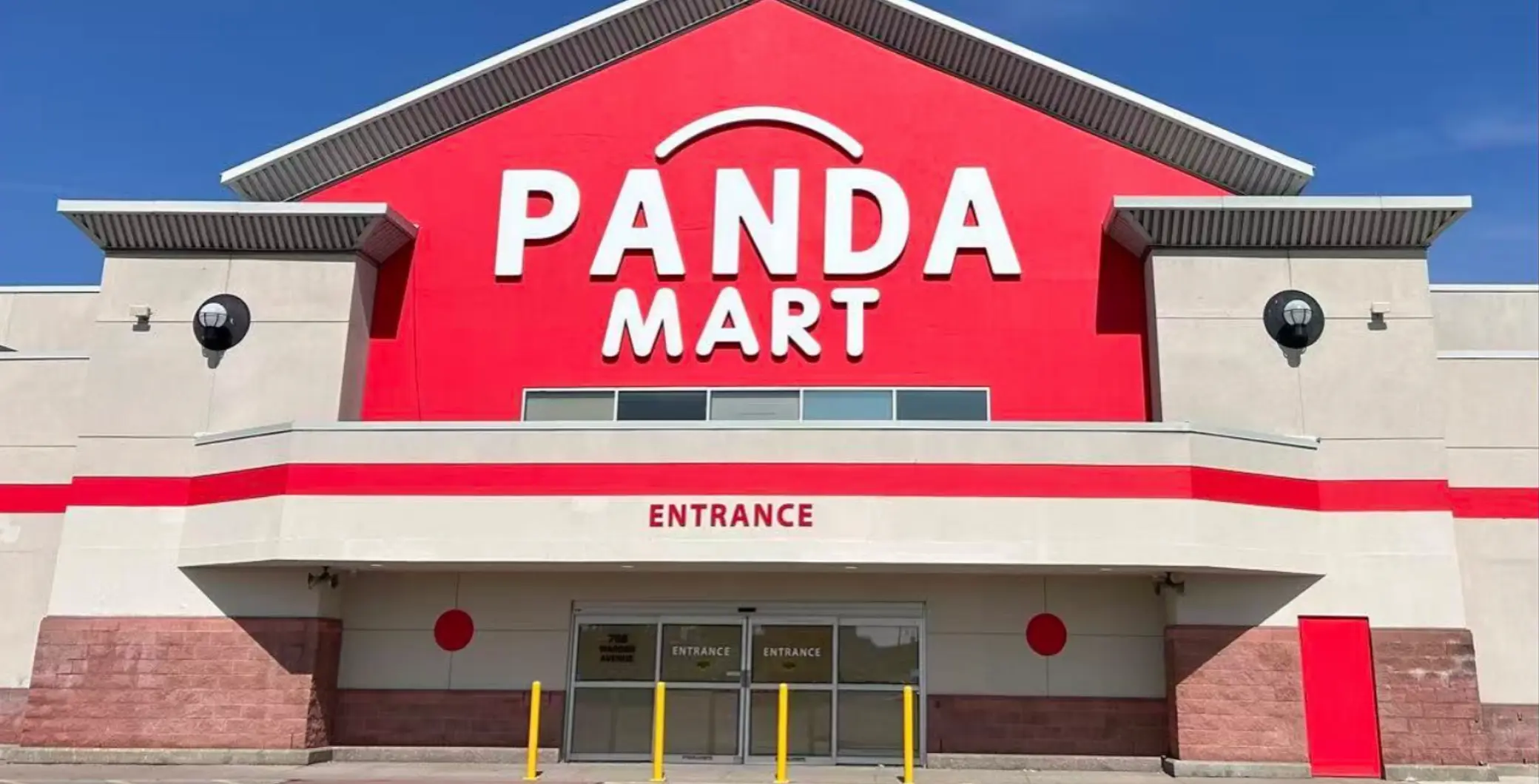 Bright exterior of Panda Mart retail store with red and white signage, storefront entrance with yellow security barriers, and bold marketing in a shopping centre.