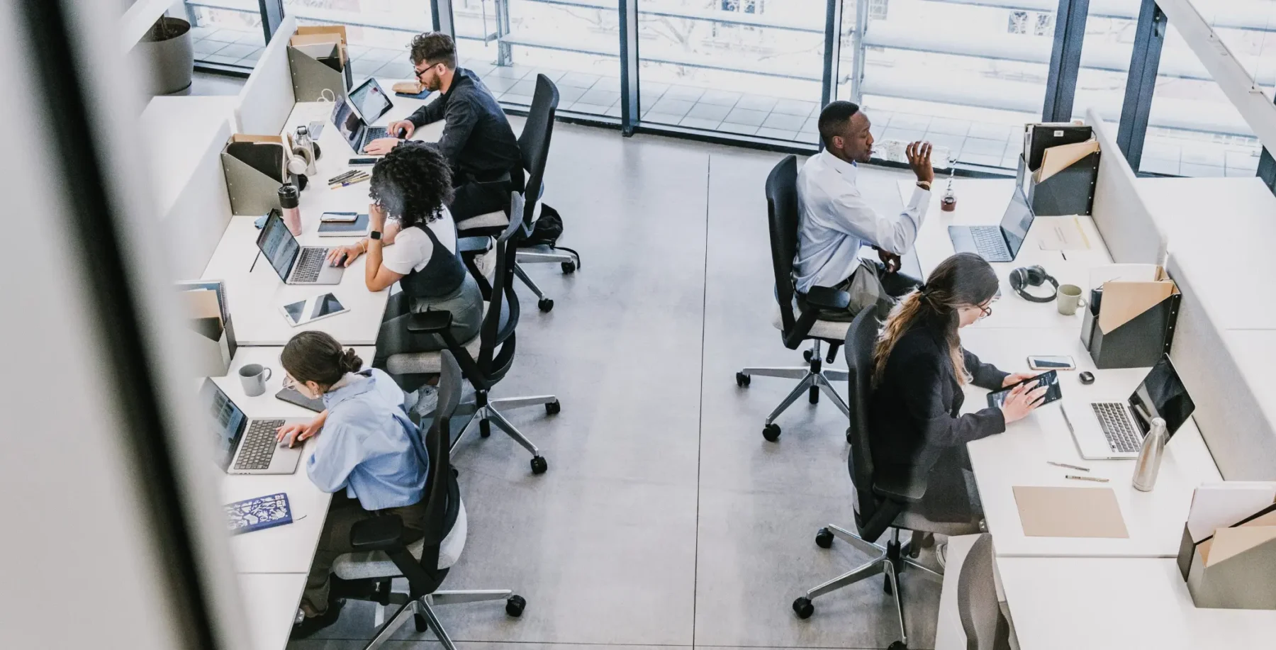 Modern Toronto office workspace with diverse professionals working on laptops and tablets, featuring large windows with city views, technology, and coworking environment.