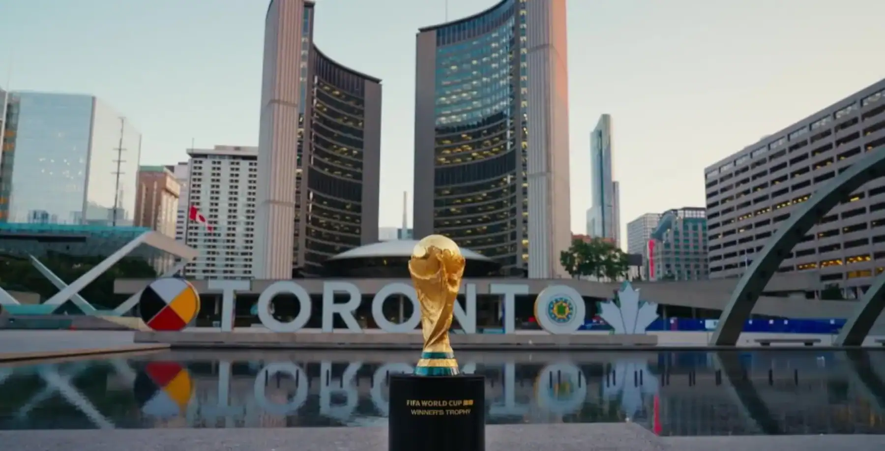 FIFA World Cup trophy displayed in Toronto's downtown Union Station area with city skyline background.