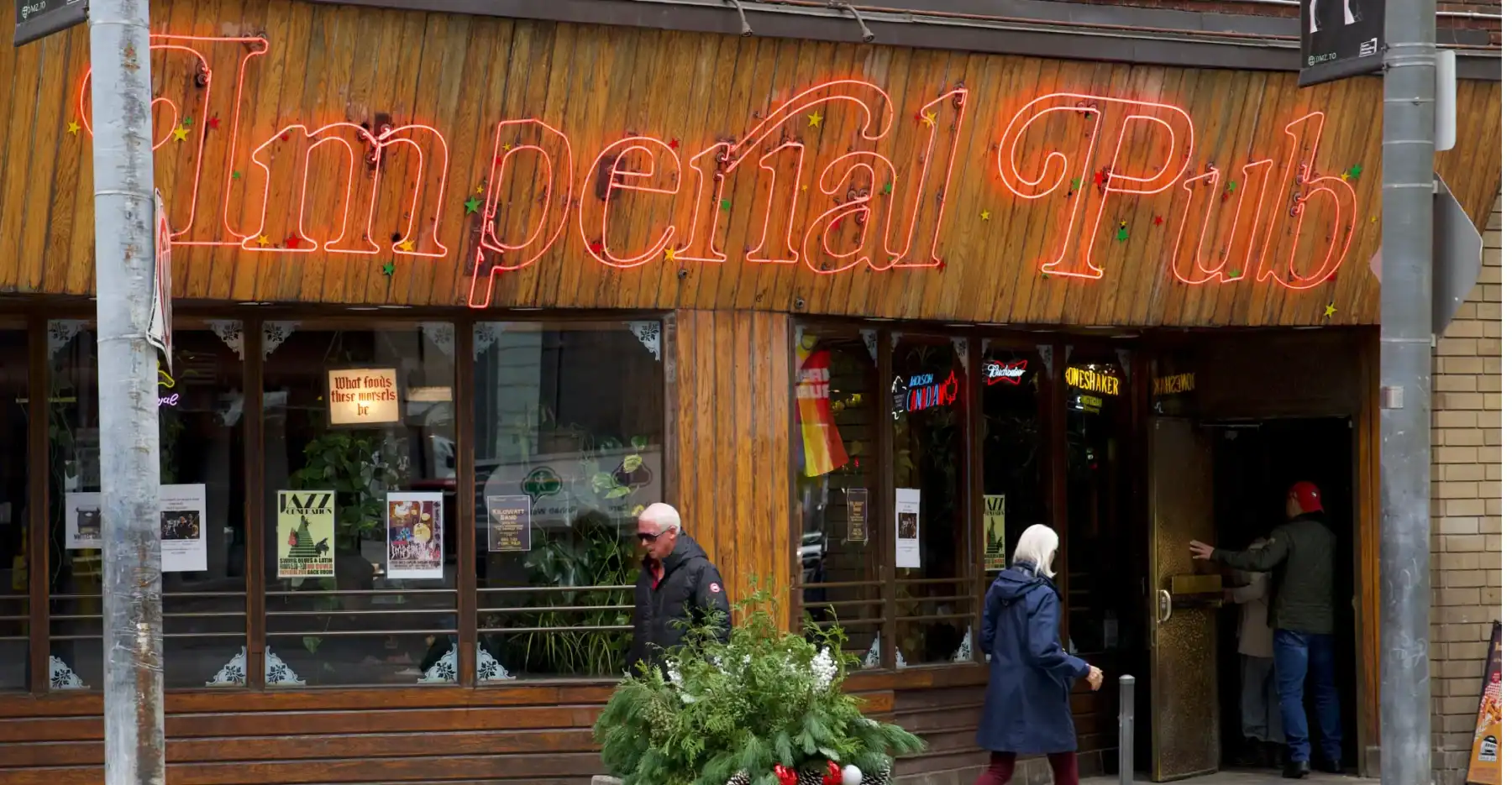 Vibrant neon sign reading "Limpelal Pub" outside a cozy Toronto bar with pedestrians and festive decorations, showcasing Toronto's lively nightlife scene and popular pub culture.