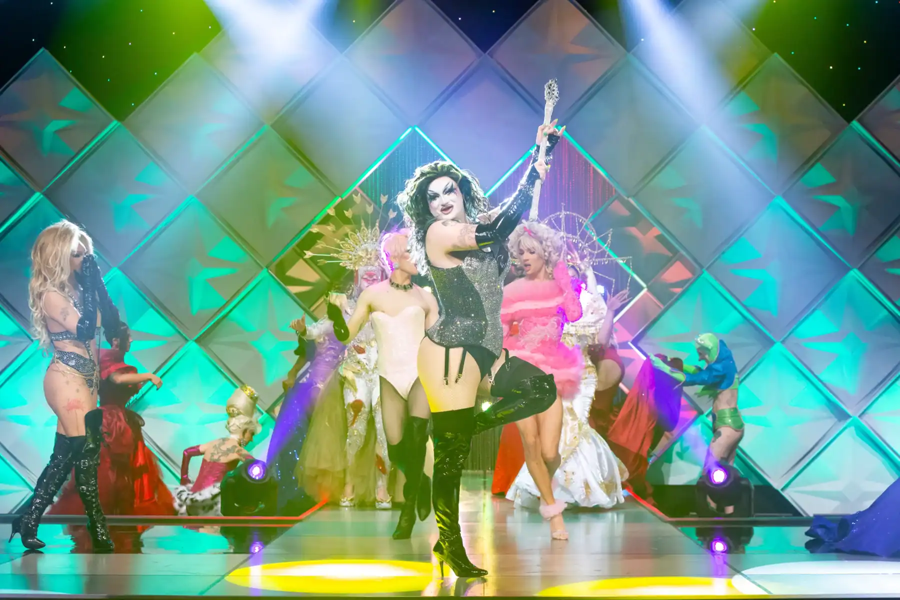 Vivid drag show performance featuring diverse performers in elaborate costumes on a colorful stage in Toronto.