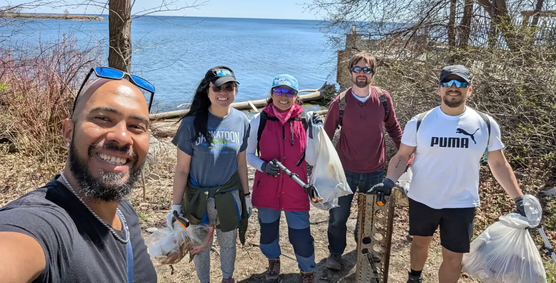 A group of diverse volunteers, including men and women, cleaning up Toronto’s shoreline and parks, promoting environmental conservation and community engagement.