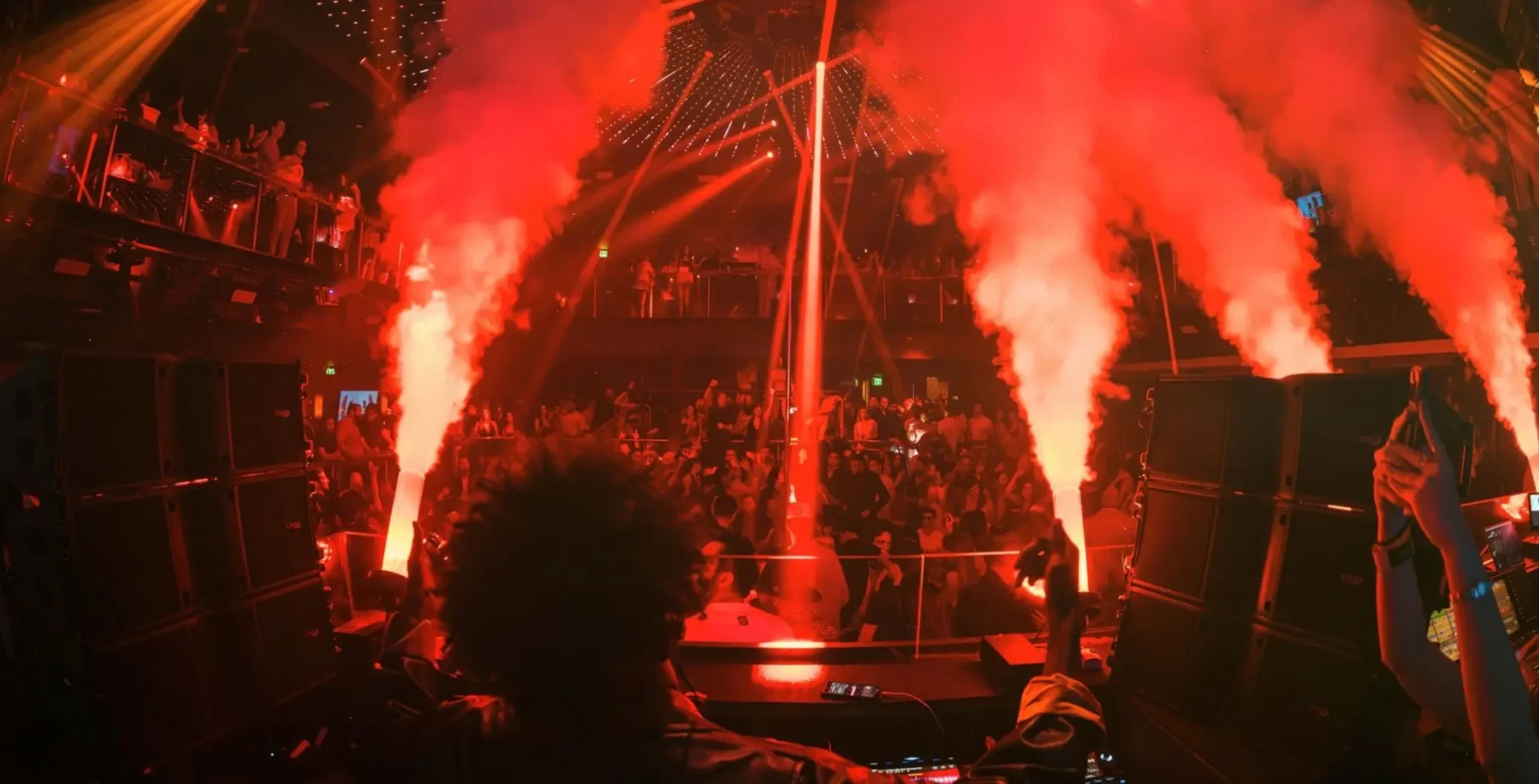 A DJ performs at a lively Toronto nightclub with energetic crowd and dynamic lighting, highlighting the city's vibrant nightlife scene.