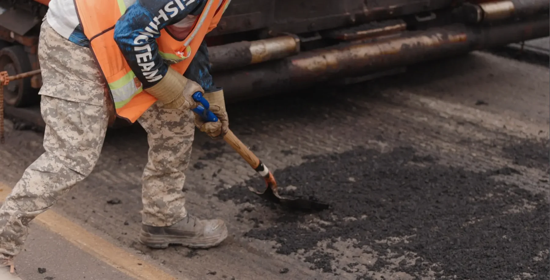 A construction worker in safety gear is patching asphalt on a Toronto road during DVP and Gardiner closures.