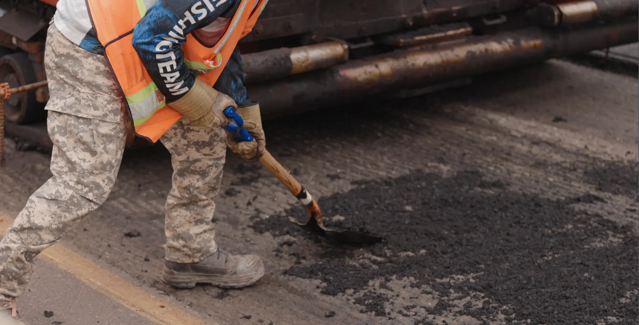 A construction worker in safety gear is patching asphalt on a Toronto road during DVP and Gardiner closures.