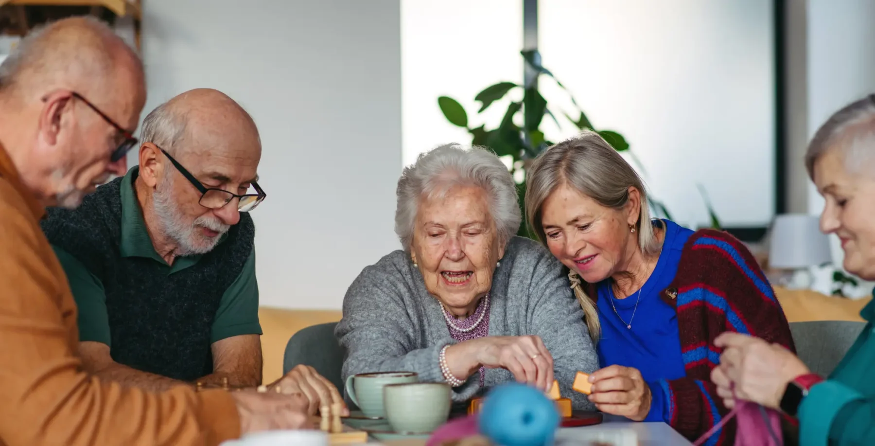 An elderly woman and caregivers enjoying a social activity, highlighting government support initiatives for seniors' well-being and community engagement in Canada.