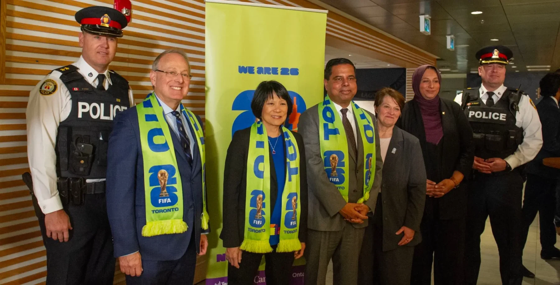 Police officers and FIFA representatives pose together at a FIFA World Cup promotional event in Toronto, highlighting community engagement and international sports collaboration.
