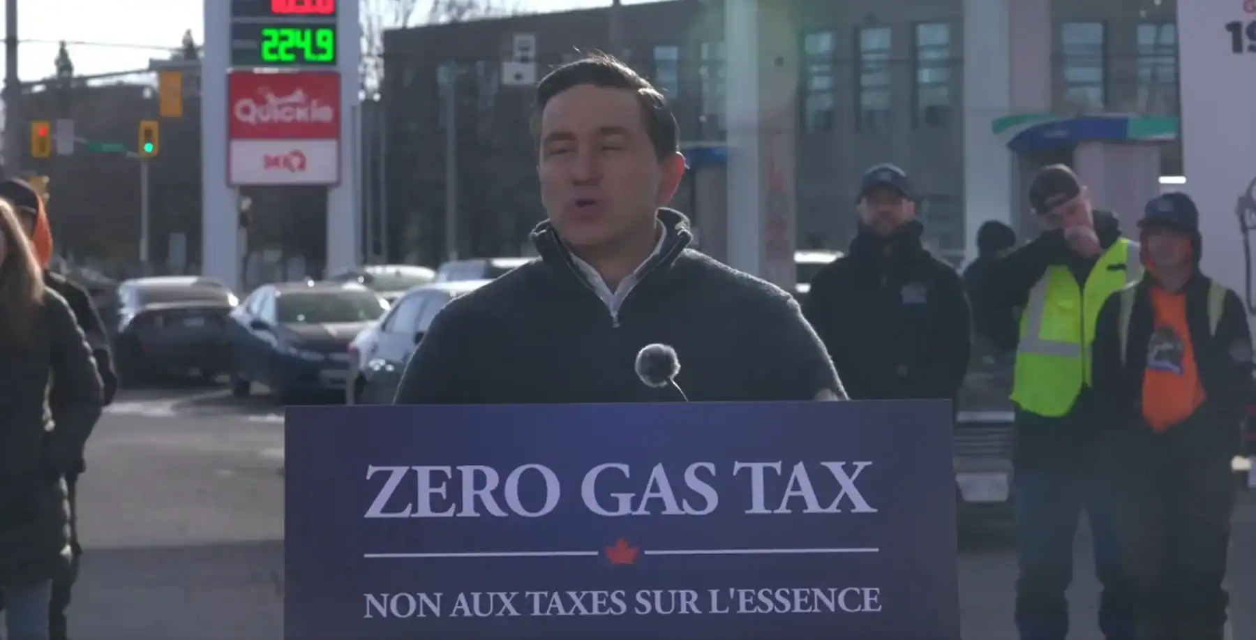 Toronto protest against high gas prices with a speaker holding a sign that reads "Zero Gas Tax," highlighting political debates on fuel taxes and economic policies.