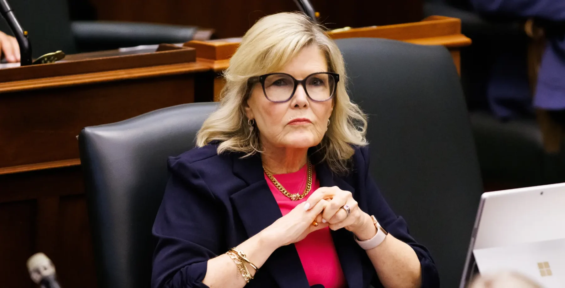 An Ontario Liberal MPP, wearing glasses and a navy blazer, seated in a legislative chamber, reflecting on political accountability and leadership.