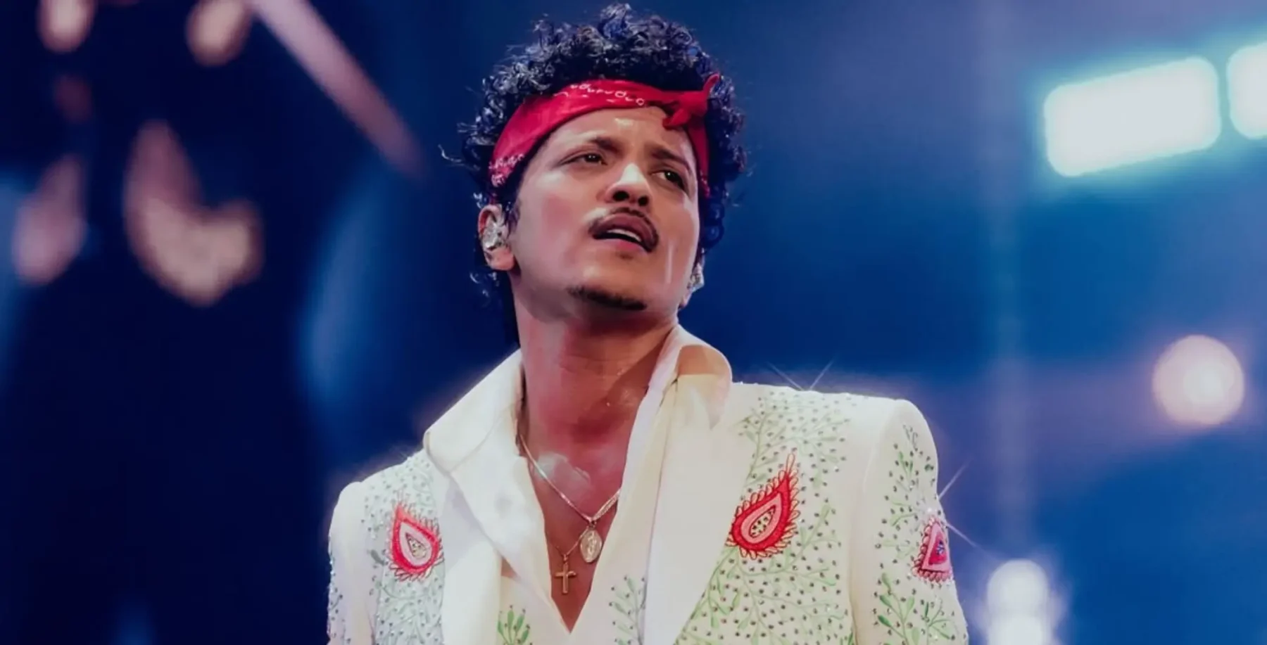 Elvis Presley impersonator performing live on stage, dressed in iconic white jumpsuit with red accents, under vibrant concert lighting, capturing the essence of a legendary music icon.