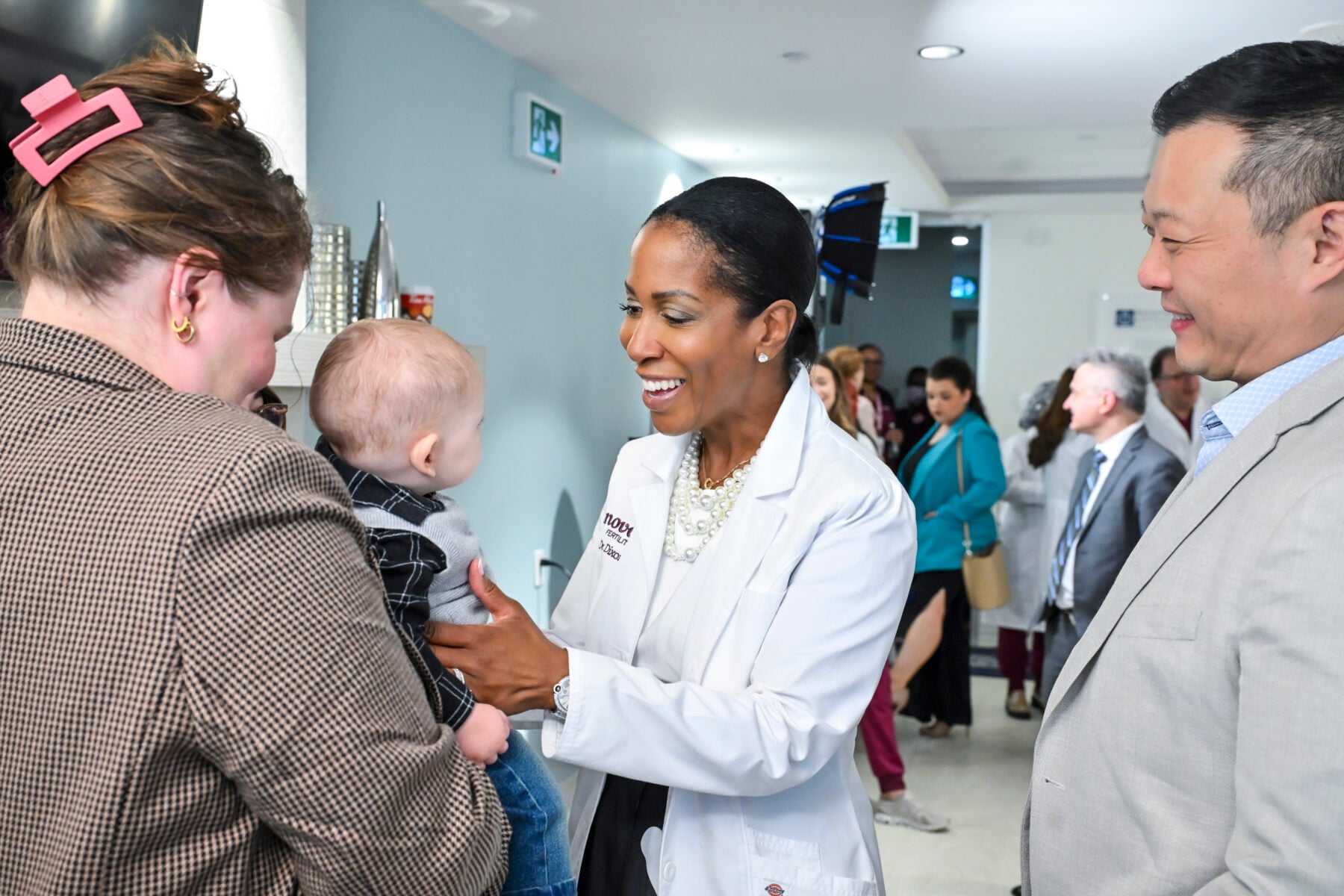 A healthcare professional smiling and talking to a mother holding her baby at a health event in Toronto, showcasing community health services.