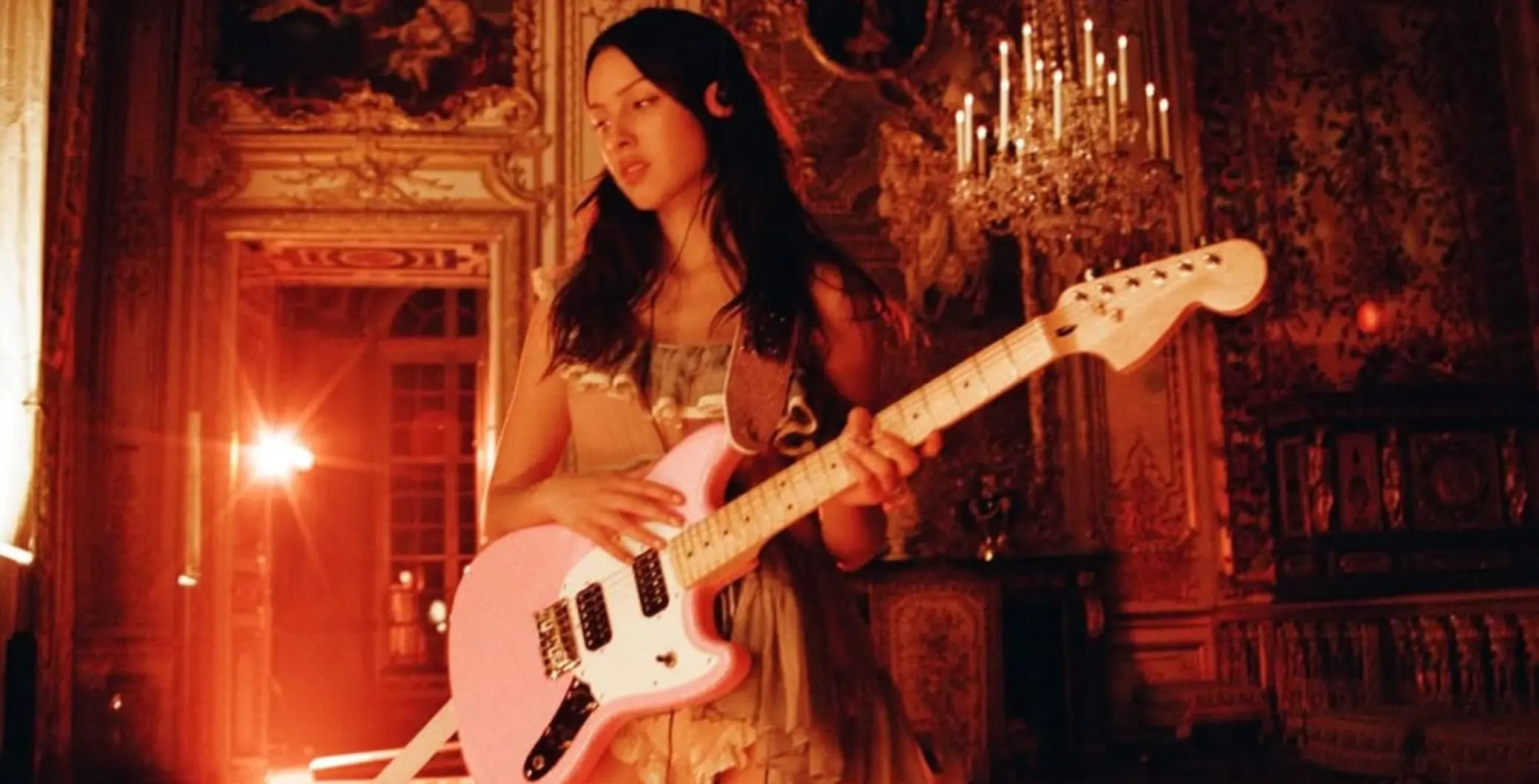Olivia Rodrigo playing an electric guitar on stage in an elegant, ornate setting, highlighting her upcoming tour and affordable ticket options this fall.