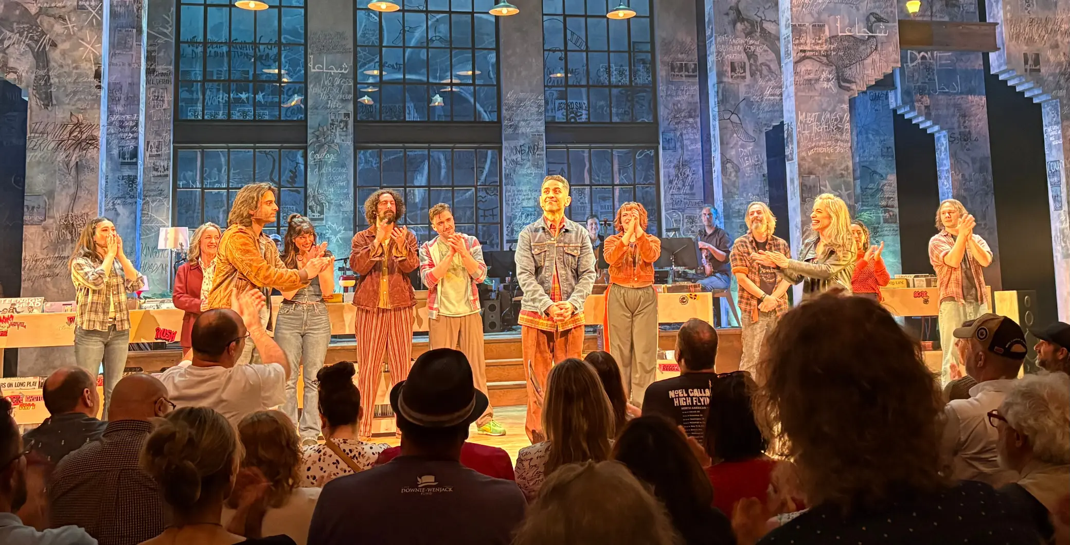 A diverse group of performers on stage during a live concert at NOW Toronto, engaging the audience with energetic music and colorful lighting in an industrial-style venue.