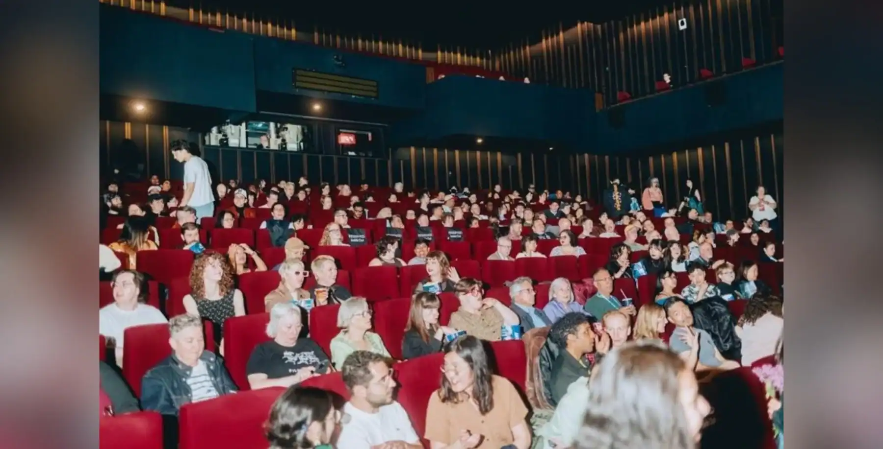 Large audience seated in a modern Toronto cinema theater with red chairs, watching a film, showcasing entertainment and cultural events in Toronto.