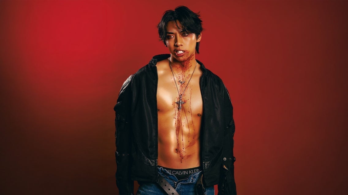 Mad Tsai performing on stage during The Bite Back Tour, shirtless with a black jacket, against a red background, showcasing his energetic presence.