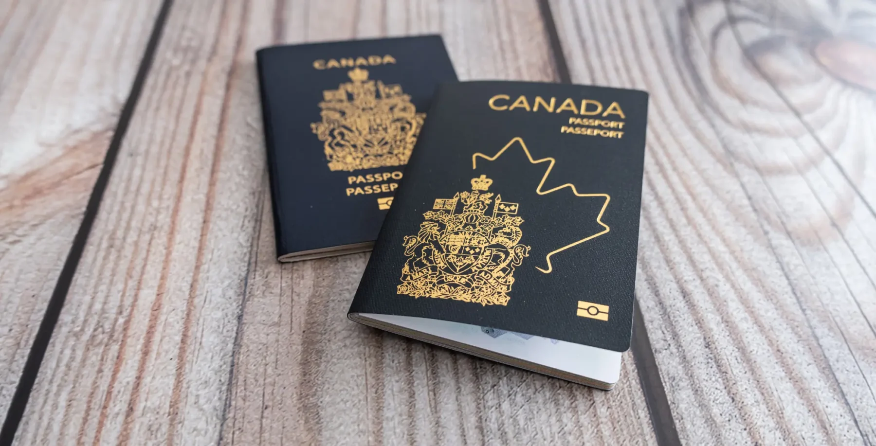 Two Canadian passports on a wooden surface, symbolizing online passport renewal services in Canada.