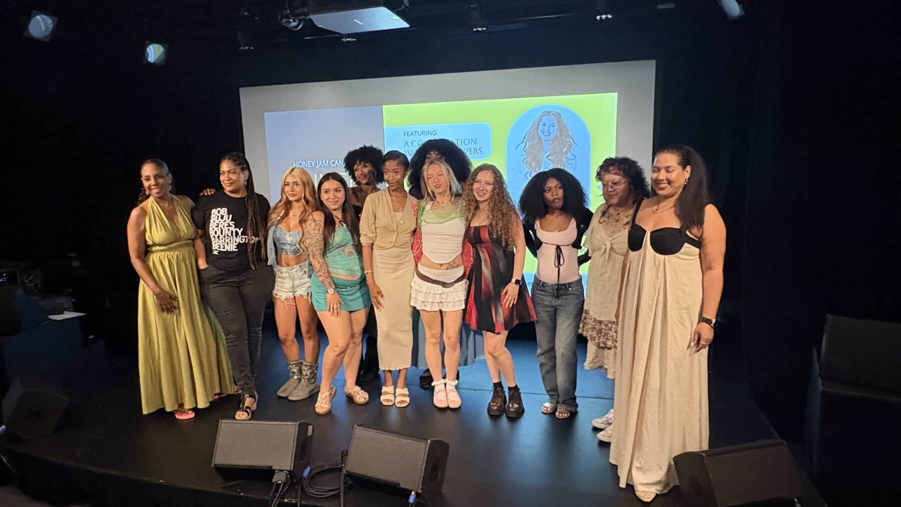 Group of 12 emerging artists at Honey Jam 2026 Toronto showcase, standing on stage with a screen behind them displaying event graphics.