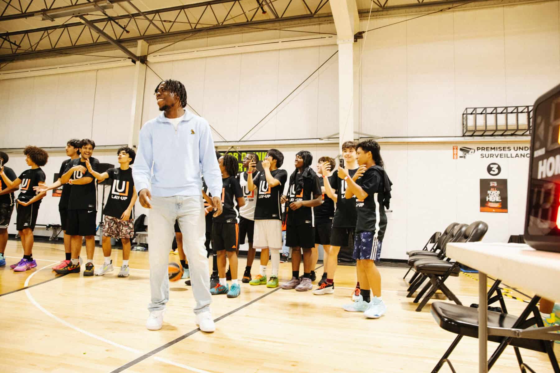Toronto basketball coach with young players in gym, inspiring youth through sports, part of a community program in Toronto.