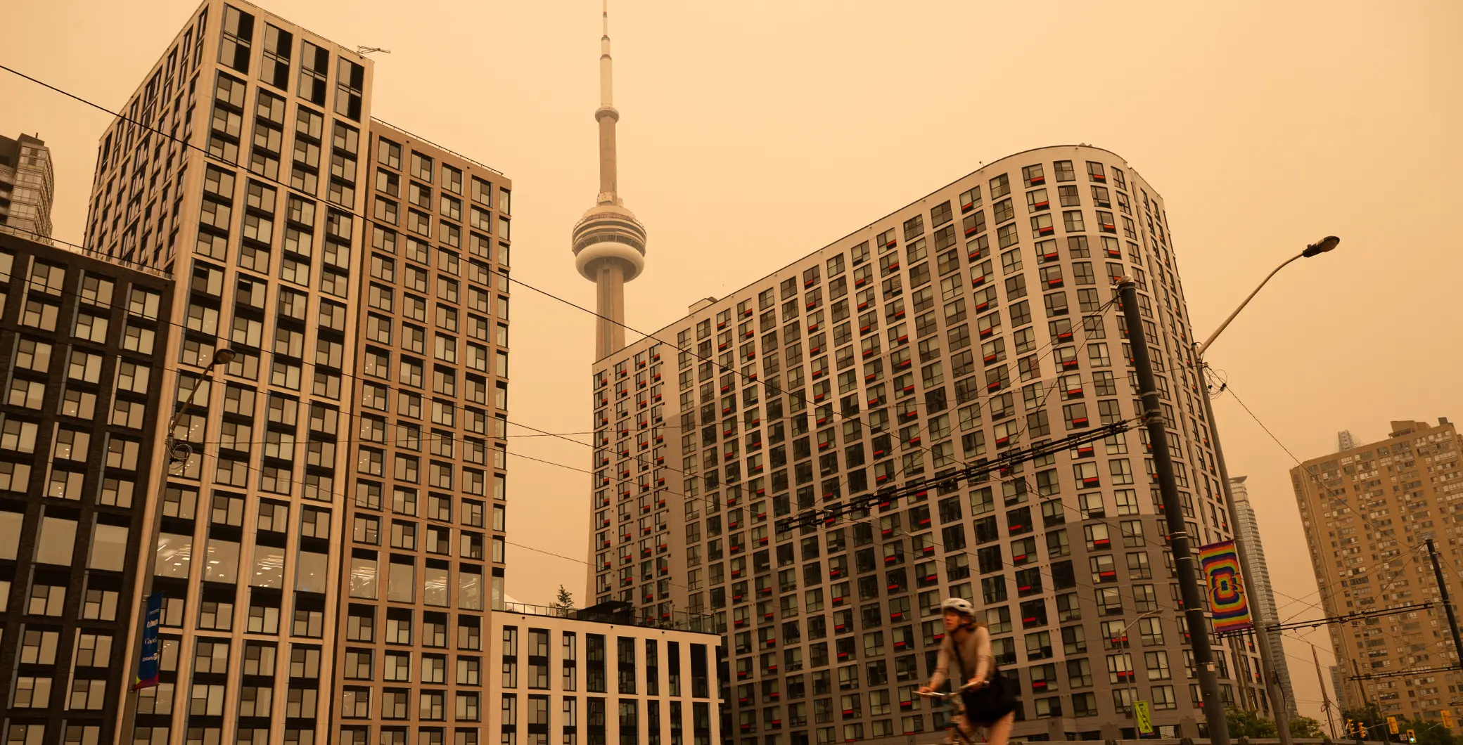 Toronto skyline shrouded in wildfire smoke with CN Tower visible in the background during hazy conditions.
