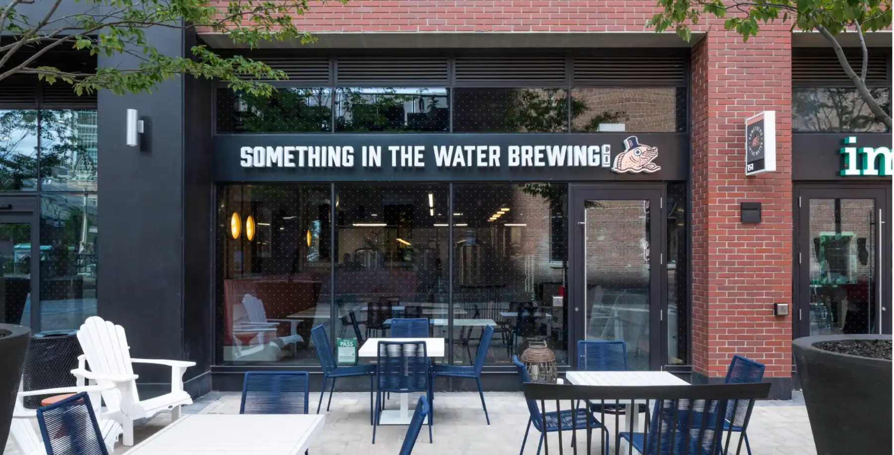 Exterior view of Something in the Water Brewing, a brewery with outdoor seating and a sign displaying its name in Toronto.