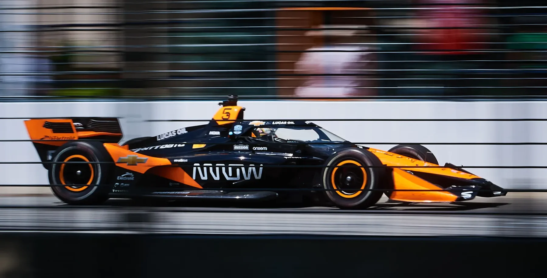 Orange and black Formula 1 race car speeding on a track with blurred background, showcasing high performance and aerodynamics.