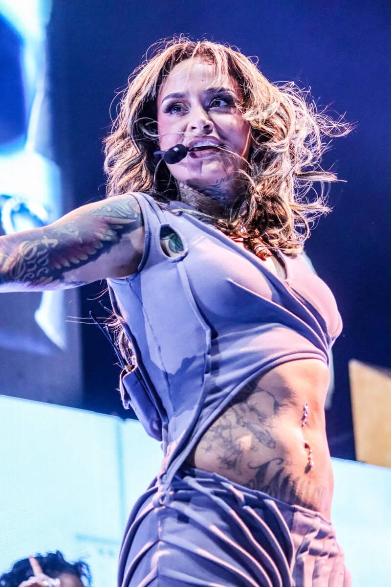 Kehlani performing on stage in Toronto, wearing a purple outfit, with tattoos visible and a confident expression, capturing a vibrant and energetic moment.