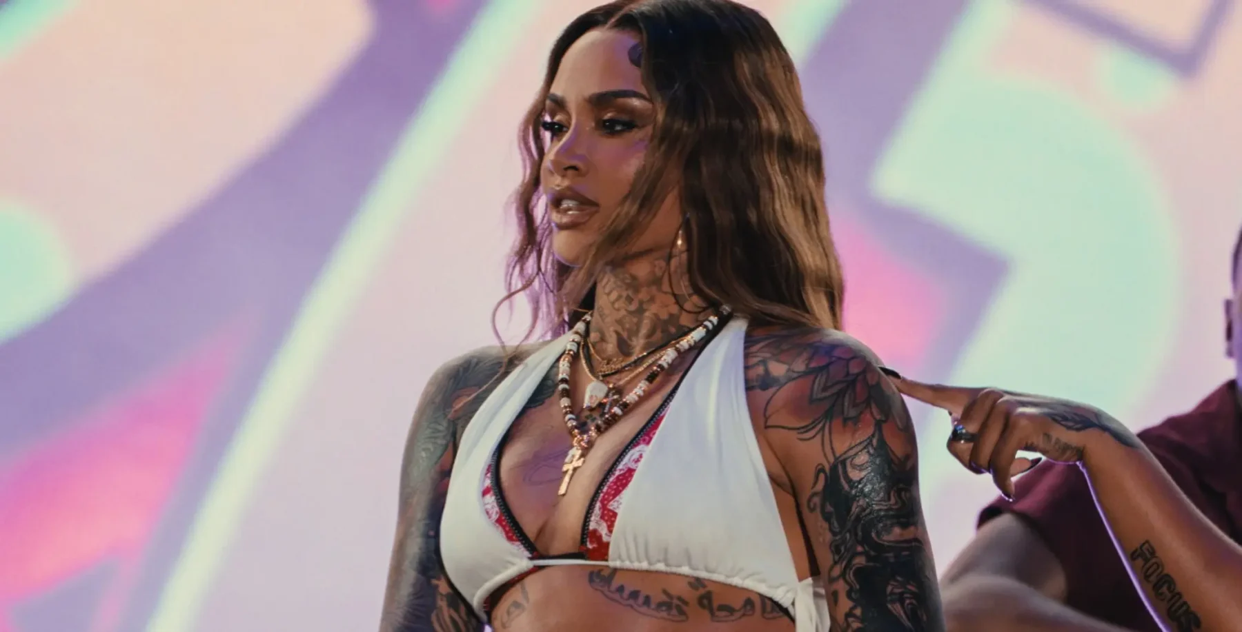 Kehlani performing at a Toronto concert, showcasing her tattoos and stylish outfit, with a vibrant stage background and dynamic lighting.
