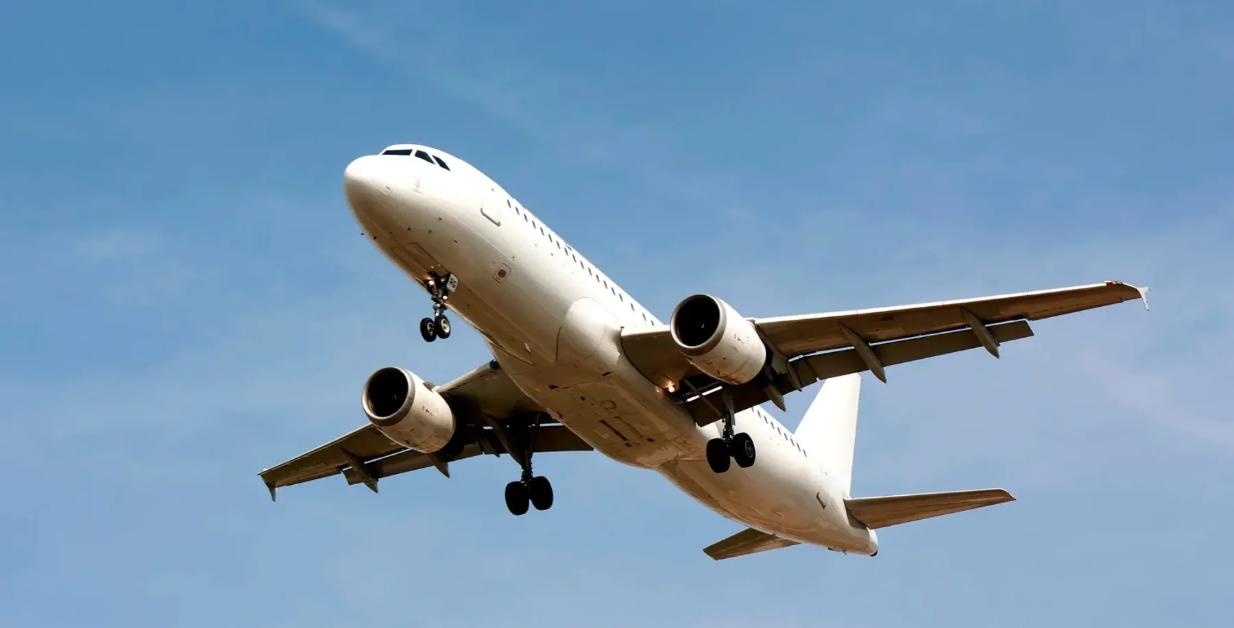 Commercial airplane in flight against a clear blue sky, preparing to land or take off, symbolizing travel and vacation opportunities.