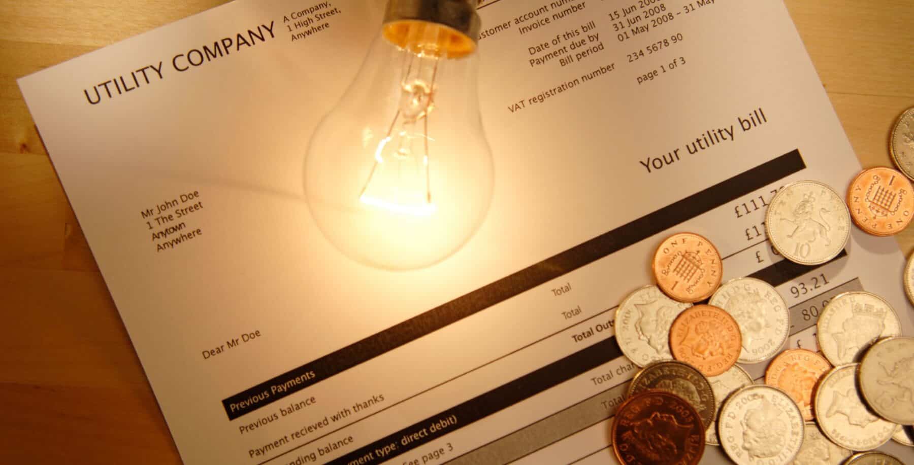 Electricity bill with coins and a light bulb on top, symbolizing energy costs and rebates in Ontario.