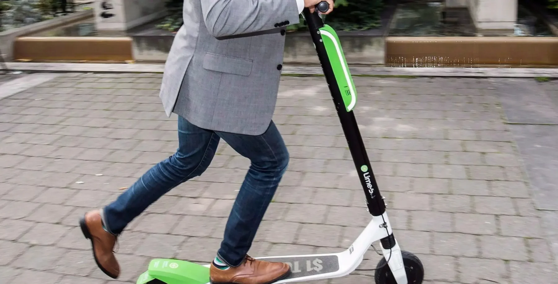 Person riding a Lime electric scooter on a city sidewalk, promoting eco-friendly transportation.