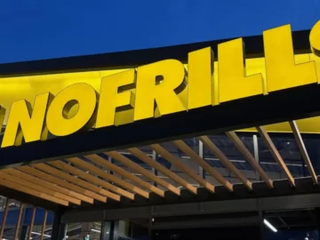 Exterior view of the newly redesigned No Frills grocery store in Ontario, featuring bold yellow signage and modern storefront, as shoppers react to affordable grocery options.