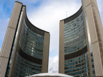 Toronto City Hall with modern curved glass towers under a partly cloudy sky.
